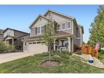 Charming two-story home featuring a well-manicured lawn, complemented by a welcoming front porch with seating at 2115 Coach House Loop, Castle Rock, CO 80109