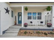 Inviting front porch featuring rocking chairs, planters, and a charming blue entry door with decorative wreath at 4422 Mt Shavano St, Brighton, CO 80601