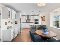 Bright kitchen features white cabinetry, stainless steel appliances, and a breakfast nook with scenic views at 1200 N Humboldt St # 1003, Denver, CO 80218