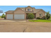 Inviting two-story home featuring a three-car garage and mature landscaping at 14825 Almstead St, Hudson, CO 80642