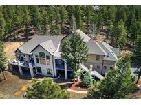 Aerial view of a grand home surrounded by lush trees, featuring multiple balconies and outdoor spaces at 26806 Evergreen Springs Rd, Evergreen, CO 80439