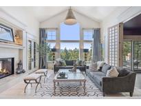Bright living room with fireplace, vaulted ceilings, large windows, and mountain views at 26806 Evergreen Springs Rd, Evergreen, CO 80439