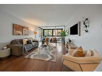 Bright living room with hardwood floors, neutral decor, balcony access, and comfortable seating arrangements at 1050 N Corona St # 202, Denver, CO 80218