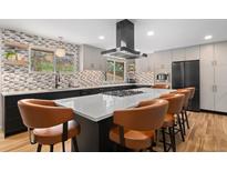 Modern kitchen with a large island, stylish barstools, stainless steel appliances, and unique backsplash at 14533 W 3Rd Ave, Golden, CO 80401