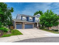 Charming blue two-story home featuring a stone accented three-car garage and a well-manicured lawn at 4688 Cedar Glen Pl, Castle Rock, CO 80109