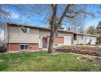 Charming split-level home featuring a brick facade, well-maintained lawn, and a quaint front garden at 10983 W Exposition Pl, Lakewood, CO 80226