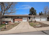 Charming home featuring a two-car garage, brick accents, and a well-manicured front yard on a sunny day at 10983 W Exposition Pl, Lakewood, CO 80226