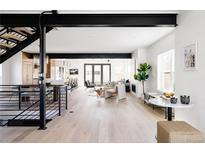 Open-concept living room with modern furnishings, natural light, and a staircase at 1880 S Adams St, Denver, CO 80210