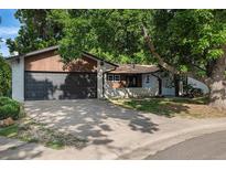 Charming single-story home with a brick facade, mature trees, and a two-car garage at 10051 E Walsh Pl, Denver, CO 80247