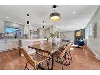 Bright open-concept dining area featuring a modern table, pendant lighting, and easy access to kitchen and living room at 3802 E Costilla Ave, Centennial, CO 80122