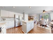 Bright kitchen boasts an island, stainless steel appliances, and transitions into an eat-in nook and living room at 2980 E 135Th Dr, Thornton, CO 80241