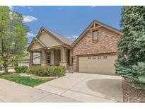 Charming home featuring brick and siding exterior, covered porch, two-car garage, and manicured landscaping at 6085 Nile Cir, Golden, CO 80403
