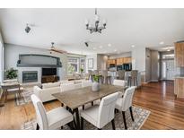 Open-concept living room showcasing a fireplace, dining area, and kitchen with hardwood flooring at 6085 Nile Cir, Golden, CO 80403