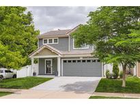 Charming two-story home featuring a well-maintained lawn, gray siding, and an attached two-car garage at 5570 Nepal St, Denver, CO 80249
