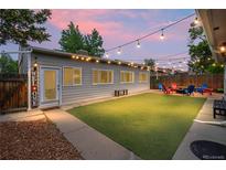 Inviting backyard features a fire pit, colorful Adirondack chairs, artificial turf and string lights at 3241 Sheridan Blvd, Wheat Ridge, CO 80212