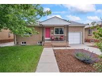 Charming brick home featuring a well-maintained front yard, walkway, and a delightful covered front porch and a one car garage at 3241 Sheridan Blvd, Wheat Ridge, CO 80212