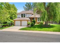 Charming two-story home featuring a well-manicured lawn, a mature weeping willow, and a convenient two-car garage at 6544 Alkire Ct, Arvada, CO 80004