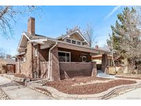 Charming brick home with a landscaped yard and inviting front porch under a clear blue sky at 1601 Jackson St, Denver, CO 80206