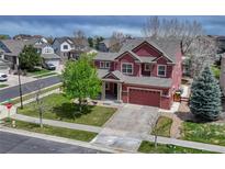 View of the two-story home with a two car garage and well-manicured lawn with mature tree at 22965 Allendale Ave, Parker, CO 80138