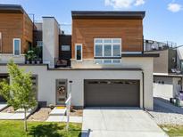 Modern three-story home with a brick and wood facade, complemented by a two-car garage and manicured lawn at 2804 W 53Rd Ave, Denver, CO 80221