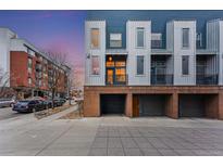 Modern townhome with steel and blue siding, brick accents, and individual garages in a vibrant neighborhood at 2680 Blake St # 12, Denver, CO 80205