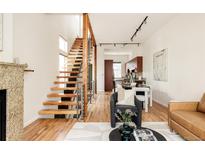 Bright living room featuring hardwood floors, modern staircase, and open layout to kitchen and dining area at 2680 Blake St # 12, Denver, CO 80205