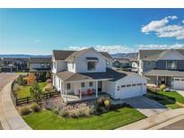 Beautiful two-story home with a welcoming front porch, manicured lawn, and mountain views on a sunny day at 11269 Star Streak Rd, Littleton, CO 80125