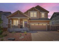 Charming two-story home featuring a covered front porch, stone accents, and a two-car garage at 24416 E Powers Ave, Aurora, CO 80016