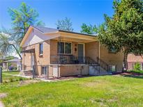 Charming brick home featuring a cozy covered front porch, landscaped yard, and mature tree at 2695 S Logan St, Denver, CO 80210