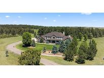 Stately two-story home on a large lot, surrounded by mature trees and landscaping, circular driveway at 36412 Paradise Cir, Elizabeth, CO 80107