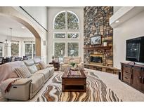 Bright living room boasts a stone fireplace, large windows, and an open layout perfect for entertaining guests at 36412 Paradise Cir, Elizabeth, CO 80107