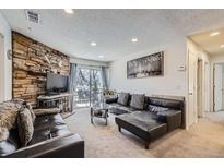 Comfortable condo living room with stone fireplace, plush seating, and access to a balcony at 4480 S Pitkin St # 128, Aurora, CO 80015