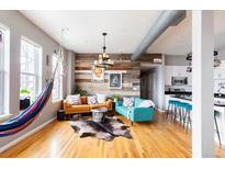 Bright living room featuring hardwood floors, modern decor, and a unique reclaimed wood accent wall at 1489 Steele St # 104, Denver, CO 80206