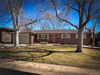 Charming brick ranch-style home with well-maintained front yard and mature trees under a bright blue sky at 1662 S Everett St, Lakewood, CO 80232