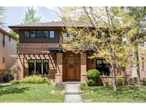 Charming two-story brick home with a meticulously landscaped front yard, covered porch and mature trees at 1143 S Saint Paul St, Denver, CO 80210