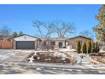 Charming ranch style home featuring a gray garage door, brick accents, and a beautifully landscaped front yard at 5121 W Plymouth Dr, Littleton, CO 80128