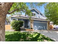 Charming blue two-story home with a well-manicured lawn, attached garage, and mature shade trees at 2691 E 132Nd Ave, Thornton, CO 80241