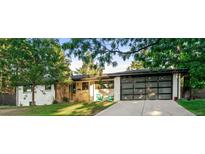 Charming home featuring lush greenery, a modern glass garage door, and a well-manicured lawn at 1920 S Niagara St, Denver, CO 80224