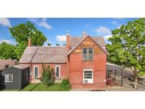 Charming red brick two-story home with a mix of brick and wood exterior, and a beautiful lawn at 805 5Th St, Fort Lupton, CO 80621