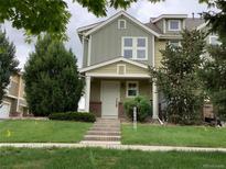Charming two-story townhome with a well-maintained lawn and inviting front porch with brick accents on the lower columns at 11947 Riverstone Cir # 7F, Henderson, CO 80640
