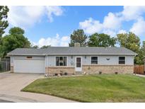 Charming single-story home with light-blue siding, brick accents, well-kept lawn, and a driveway leading to an attached garage at 6651 S Dudley Ct, Littleton, CO 80123