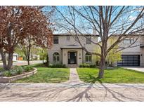 Charming two-story home with stucco exterior, well-manicured lawn, and mature trees at 2500 S Monroe St, Denver, CO 80210