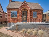 Charming brick home featuring an arched entry, complemented by well-maintained landscaping at 3921 N Raleigh St, Denver, CO 80212