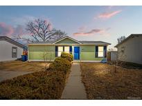 Charming single story home with light green siding, a blue door, and a well-manicured front yard at 104 Winnipeg St, Lochbuie, CO 80603
