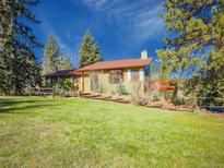 Charming single Gathering home featuring a green exterior, red trim, and a lush front lawn at 8473 Gray Fox Dr, Evergreen, CO 80439