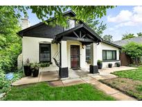 Charming painted brick home featuring a covered front porch with hanging swing at 4968 Alcott St, Denver, CO 80221
