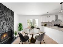 Bright dining area featuring a stone fireplace, round table, and sliding glass doors to the backyard at 558 S Field Ct, Lakewood, CO 80226