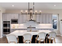 Stunning kitchen boasts gray cabinetry, a spacious island with seating, and modern stainless steel appliances at 10817 Greycliffe Dr, Highlands Ranch, CO 80126