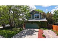 Two-story green home featuring an attached garage, large shade tree, and beautiful landscaping at 2364 Autumn Ridge Blvd, Lafayette, CO 80026