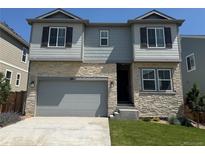Charming two-story home with a stone facade, attached garage, and well-manicured lawn at 16651 W 93Rd Ave, Arvada, CO 80007